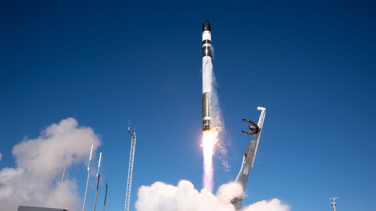 a white, red and green rocket launches into a blue sky