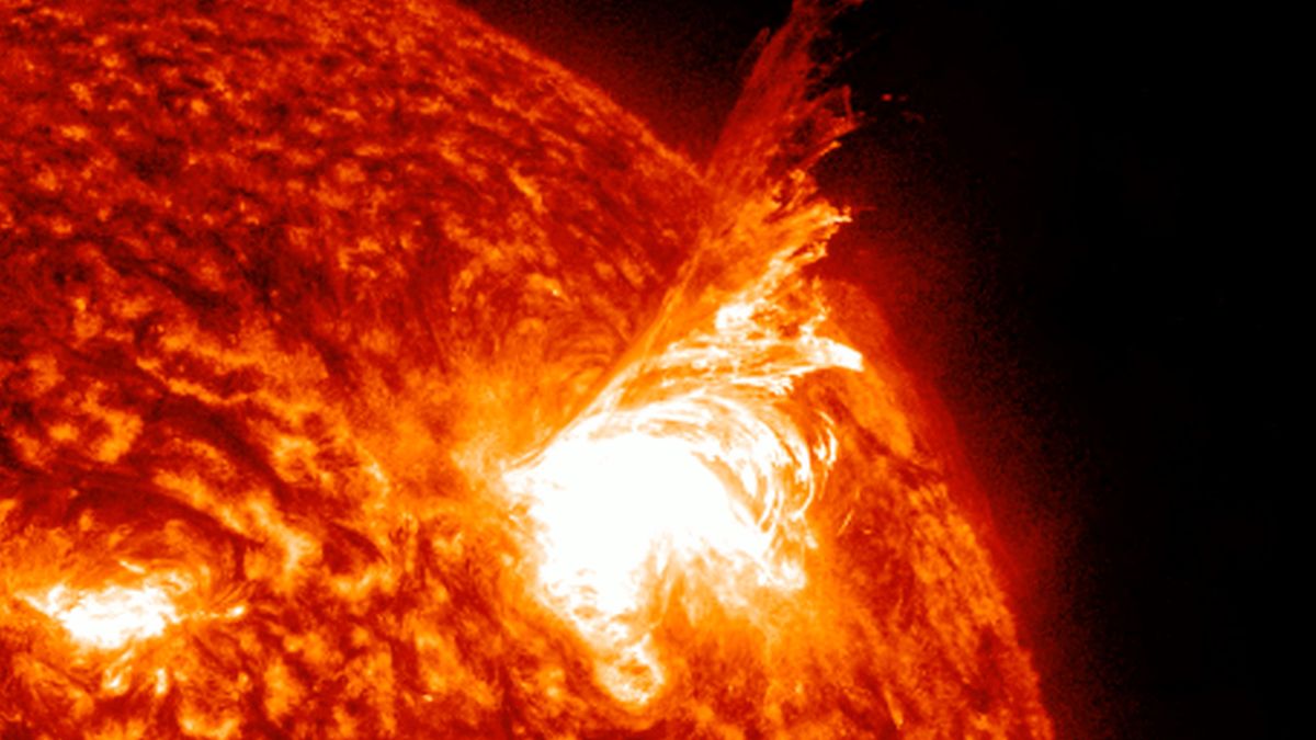 a close up still image of the sun showing a huge fiery looking tendril lashing out from the sun.