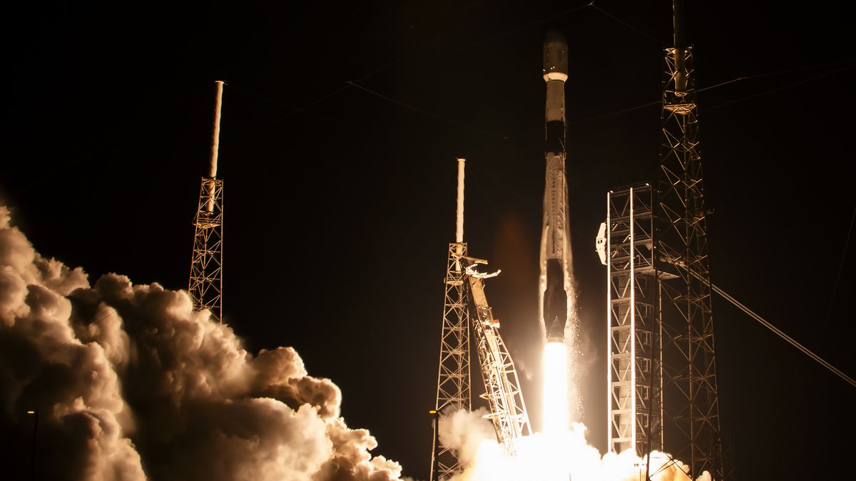 a black-and-white spacex falcon 9 rocket launches into a night sky.