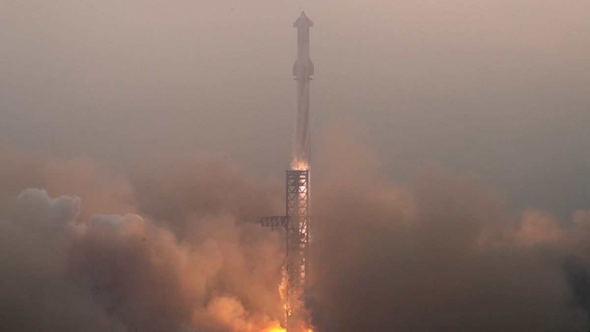 a rocket stands upright on a launch pad with the sun poking through clouds above it