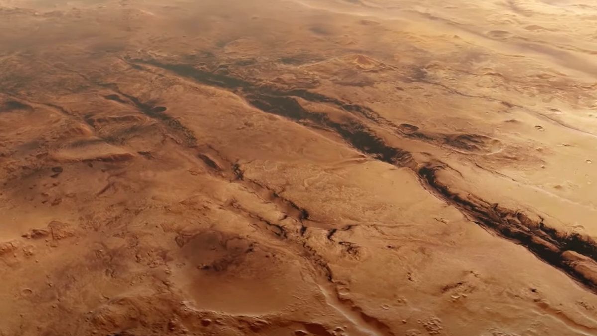 a reddish-orange landscape lined with deep trenches and ravines